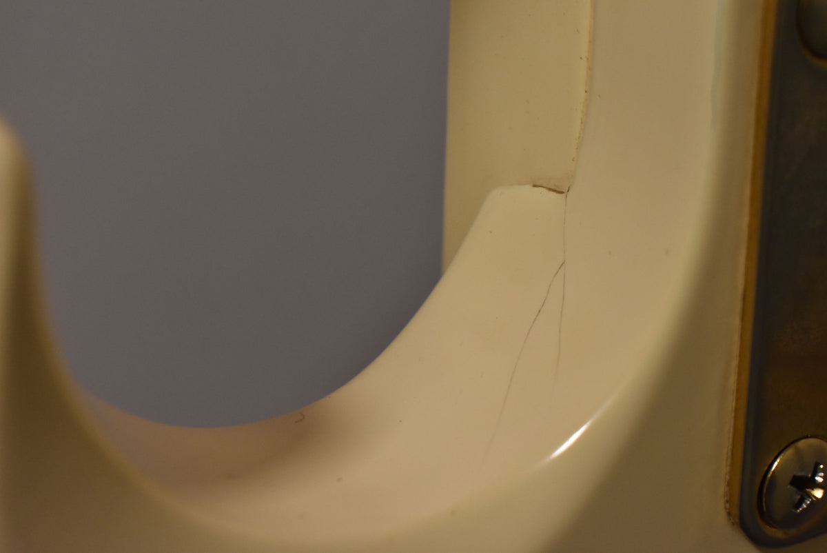 Close-up of the creamy white body, showing finish checking and a crack near the neck joint and a metal plate with a screw.