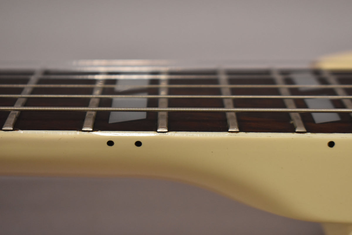 Close-up of the guitar's white neck binding and dark fretboard with block inlays, showing side dots and some fret wear.