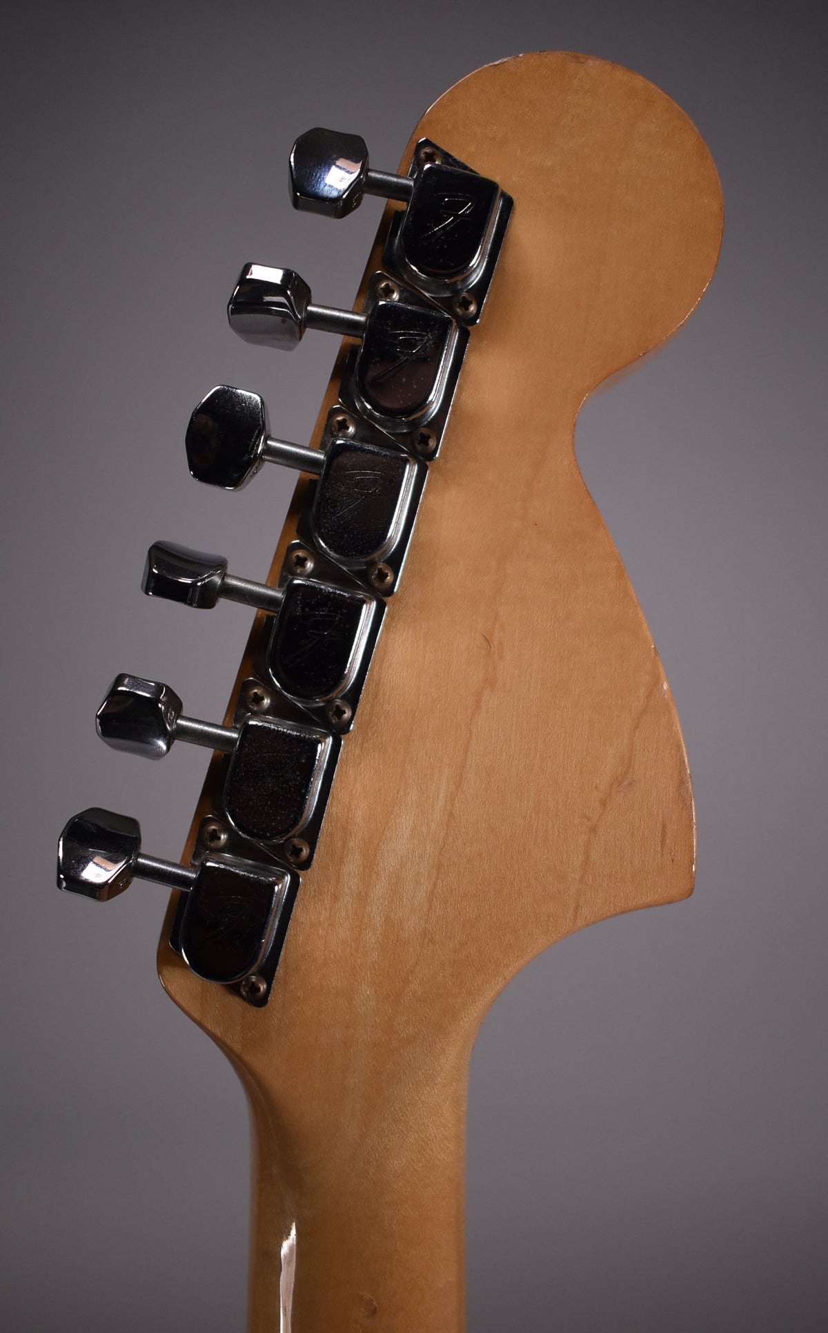 Rear view of the natural finish headstock, showing six chrome tuners with some tarnishing and light wear on the wood.