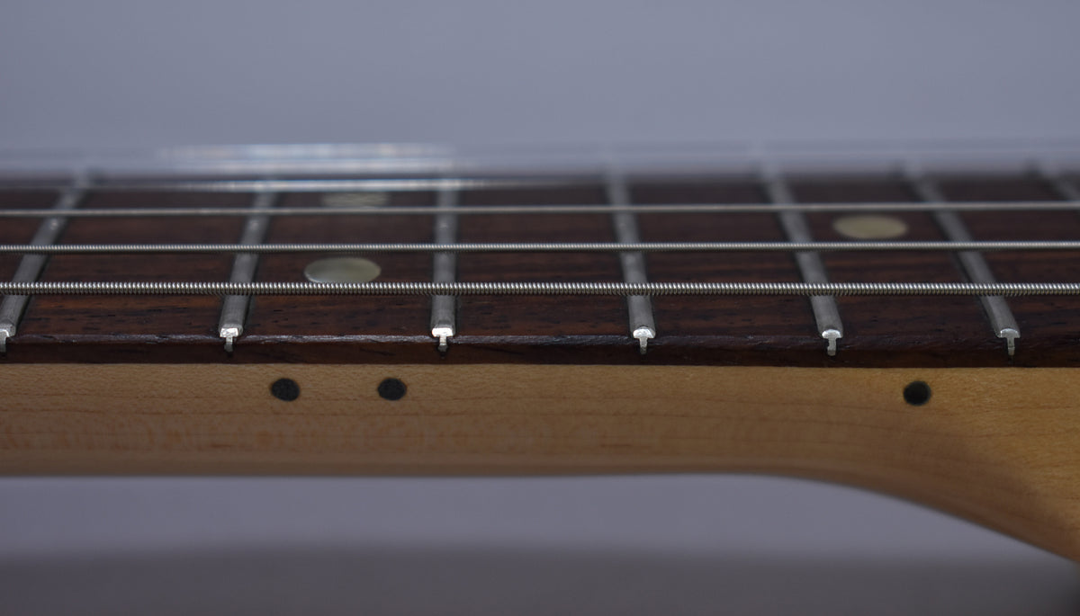 Close-up of the dark rosewood fretboard with dot inlays and frets, showing the light maple neck and side dots.