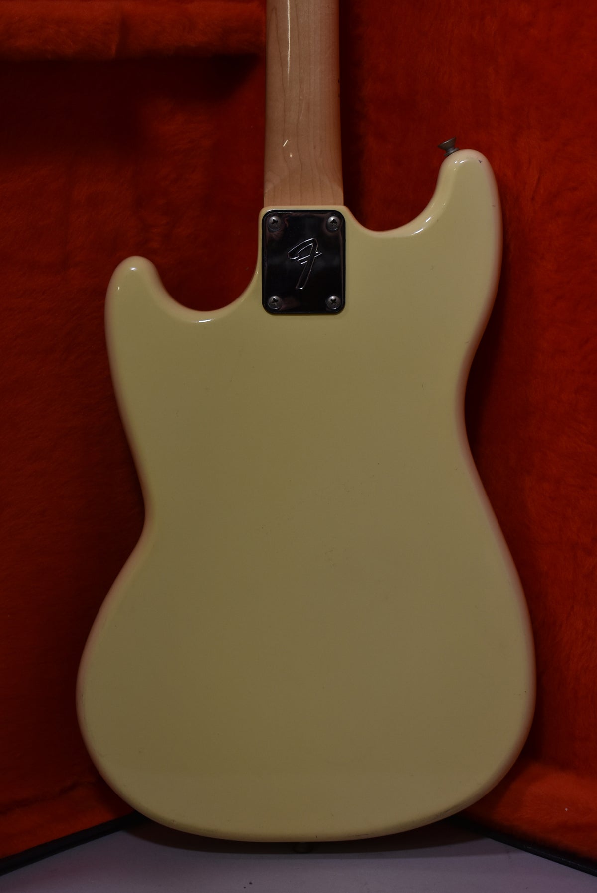 The back of an Olympic White guitar body with a maple neck and chrome neck plate, showing minor finish wear.