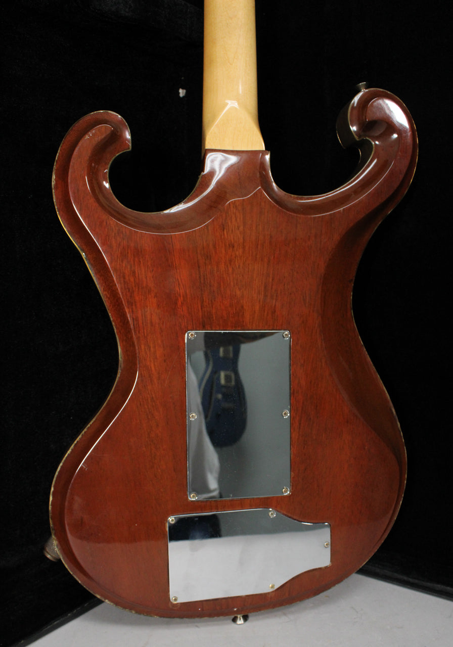 The back of a dark reddish-brown guitar with a natural maple neck, two chrome control plates, and wear along the body edges.
