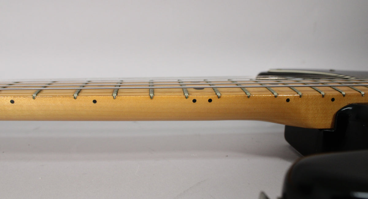 Close-up of the guitar's maple fretboard, showing the frets, strings, and black dot inlays, with some wear visible.