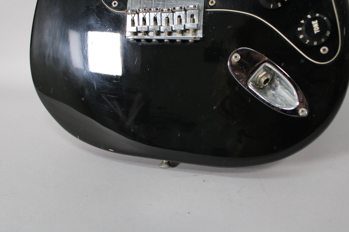 Close-up of the lower body, showing the black finish with many scratches, the chrome hardtail bridge, and the input jack.