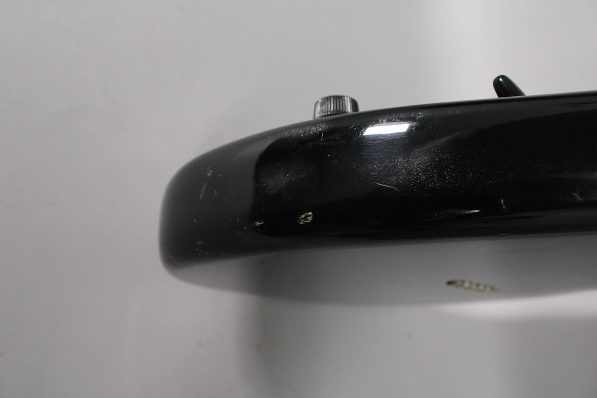 Close-up of the black guitar body's upper bout, showing surface scratches, dings, and a chrome strap button.