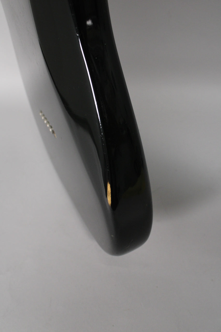 Close-up of the guitar's lower bout, showing the glossy black finish with a visible chip on the edge revealing the lighter wood underneath.