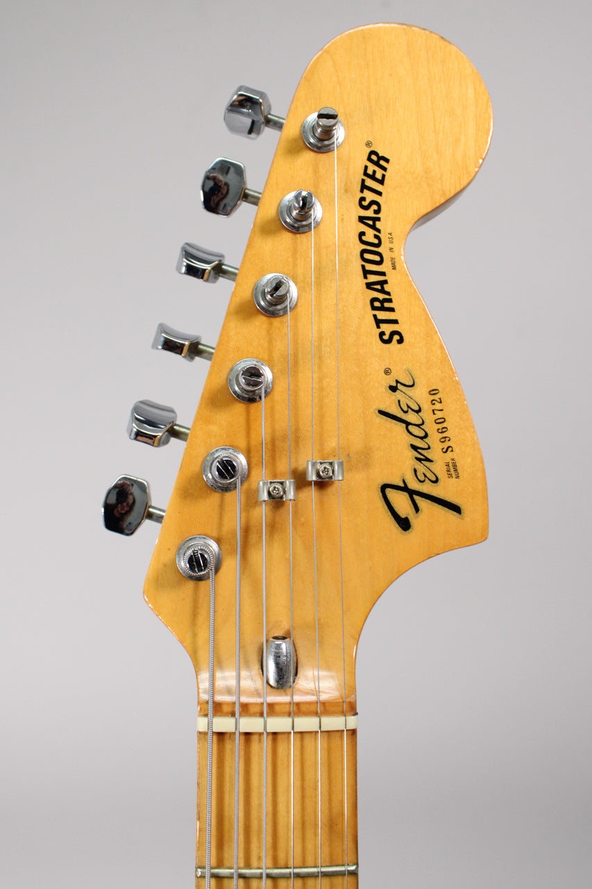 Close-up of the guitar's headstock, showing the light maple finish, six chrome tuners, and two string trees.