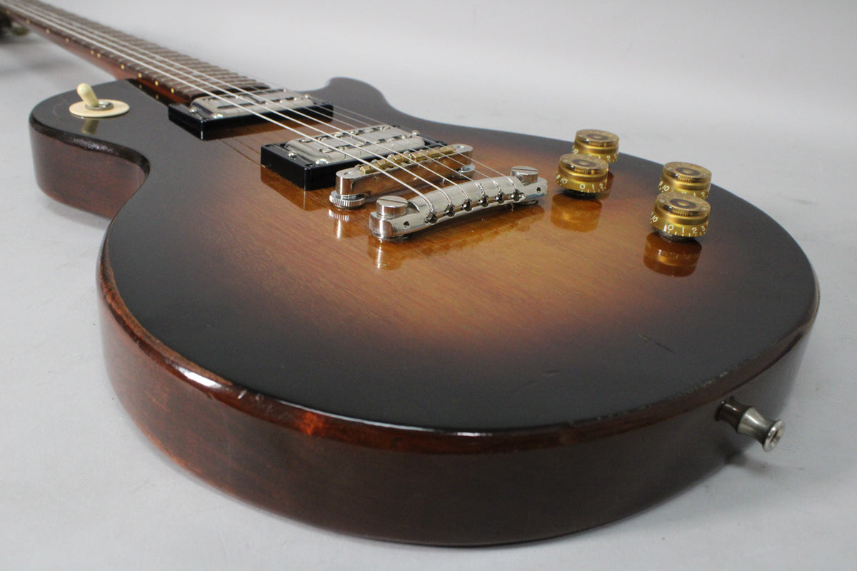 The tobacco sunburst guitar body, with chrome hardware and four gold speed knobs, shows light wear and a few small dings.