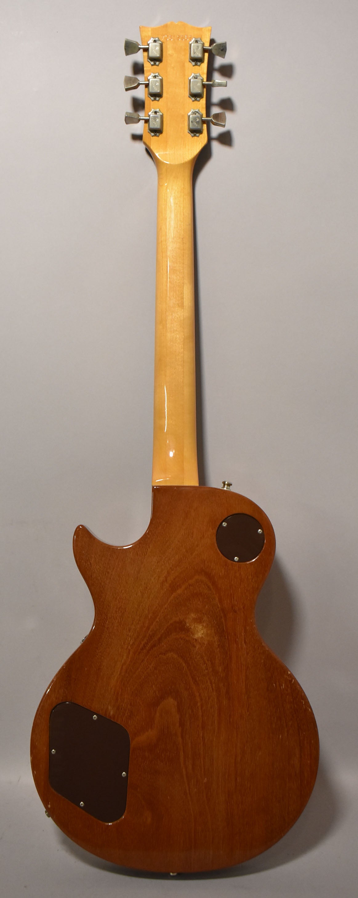 Full rear view of a glossy natural finish guitar, showing the light-colored neck and headstock with six chrome tuners.