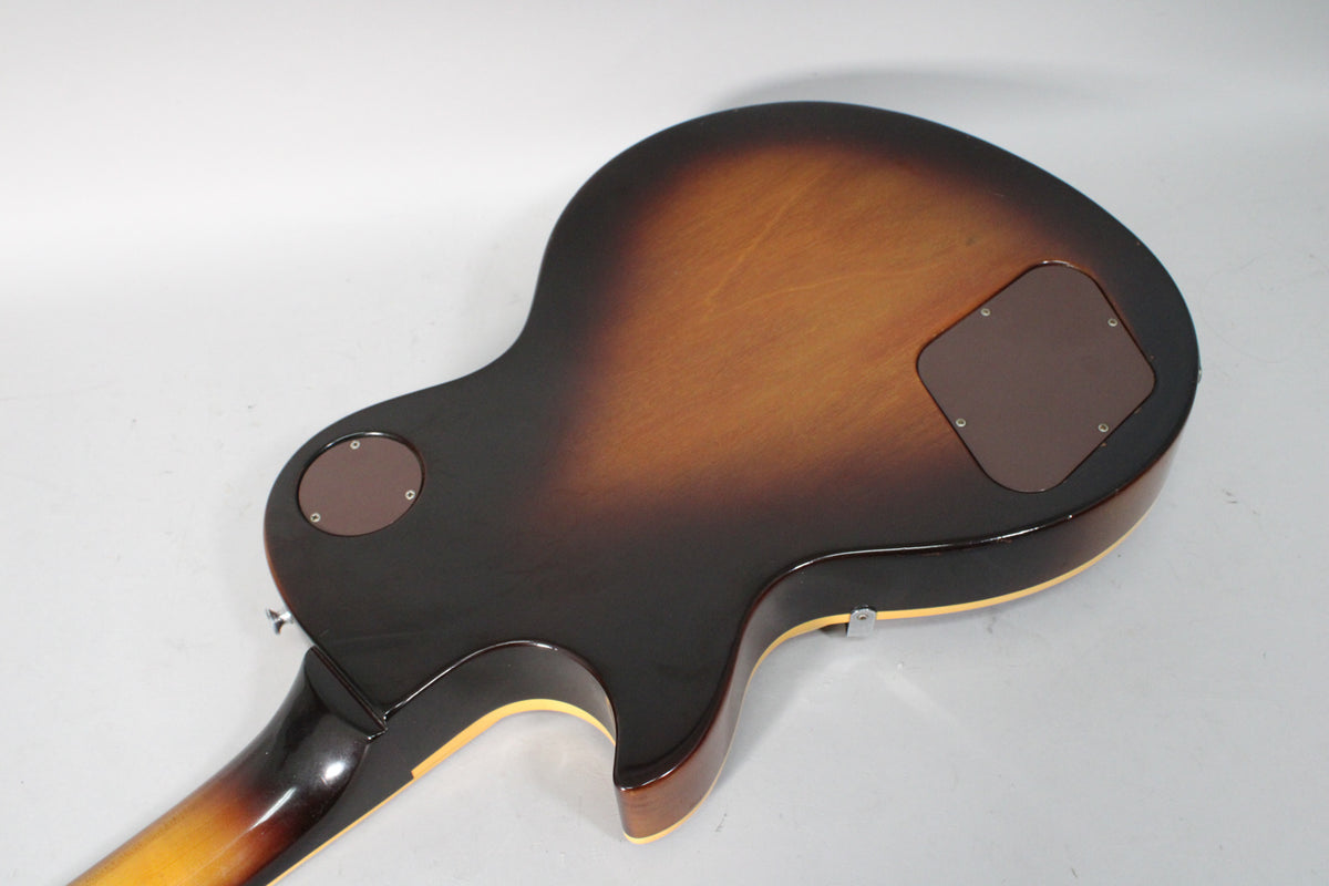 The guitar's tobacco burst back shows light scratches, two brown control cavity covers, and a visible neck joint.