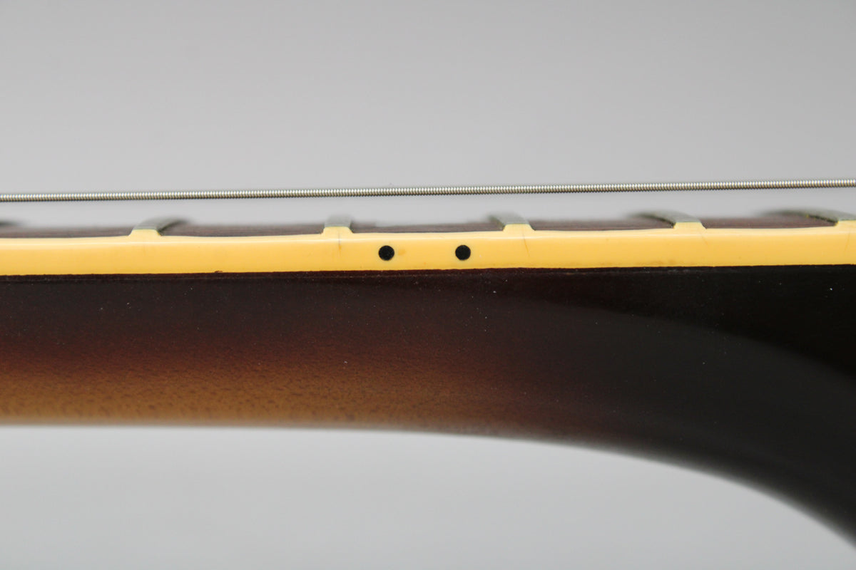 Close-up of the guitar's neck, showing the dark tobacco burst finish, cream binding, and two black side dot markers on the fretboard.