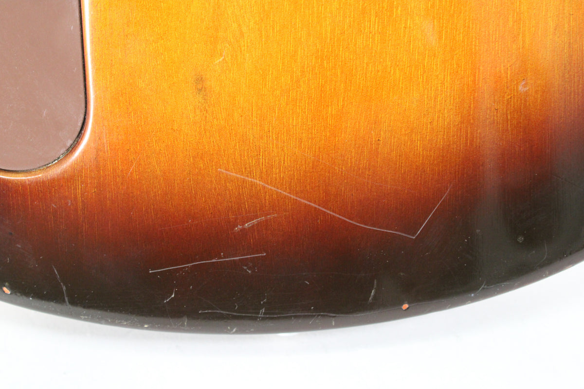 Close-up of the guitar's tobacco burst body, showing numerous scratches and scuffs on the lower bout and a control cavity cover.