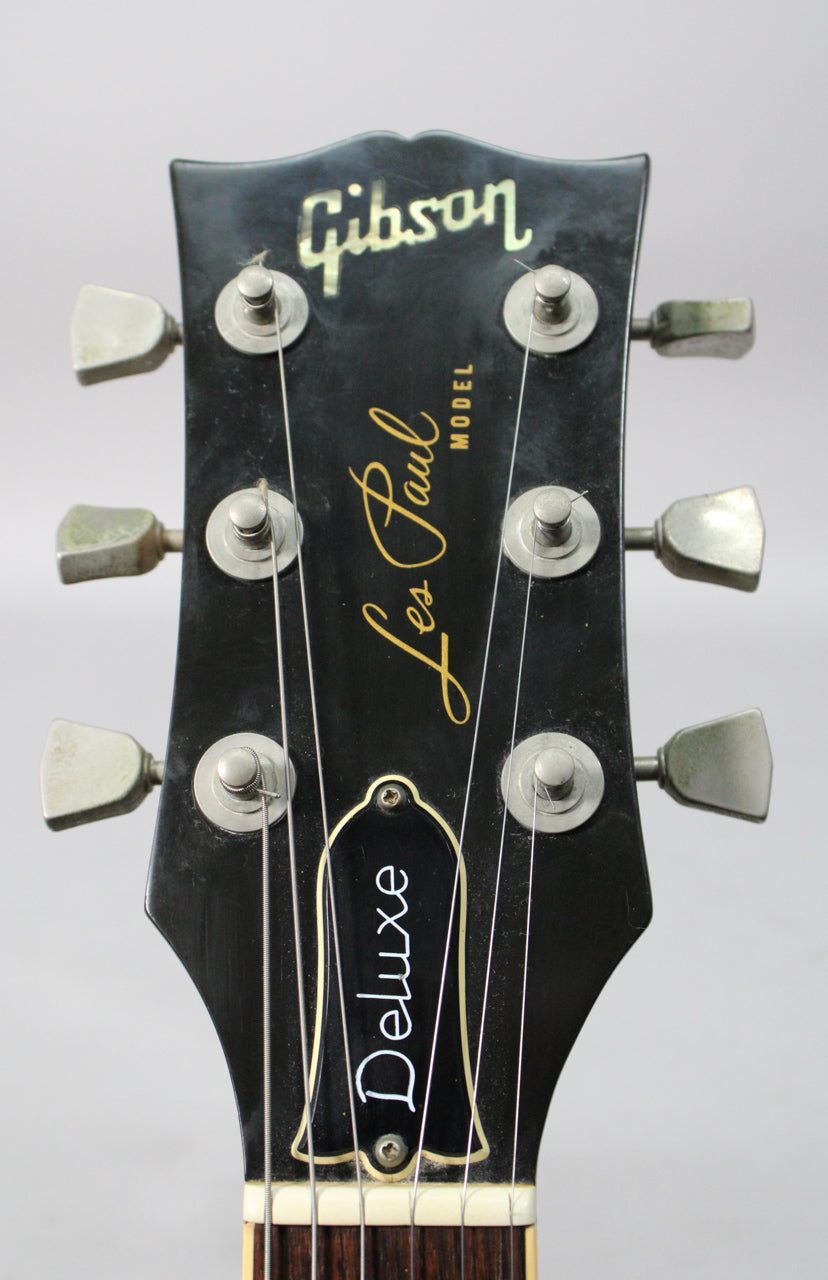 The black headstock, with six tarnished metal tuners, shows light wear and a white nut above the dark fretboard.
