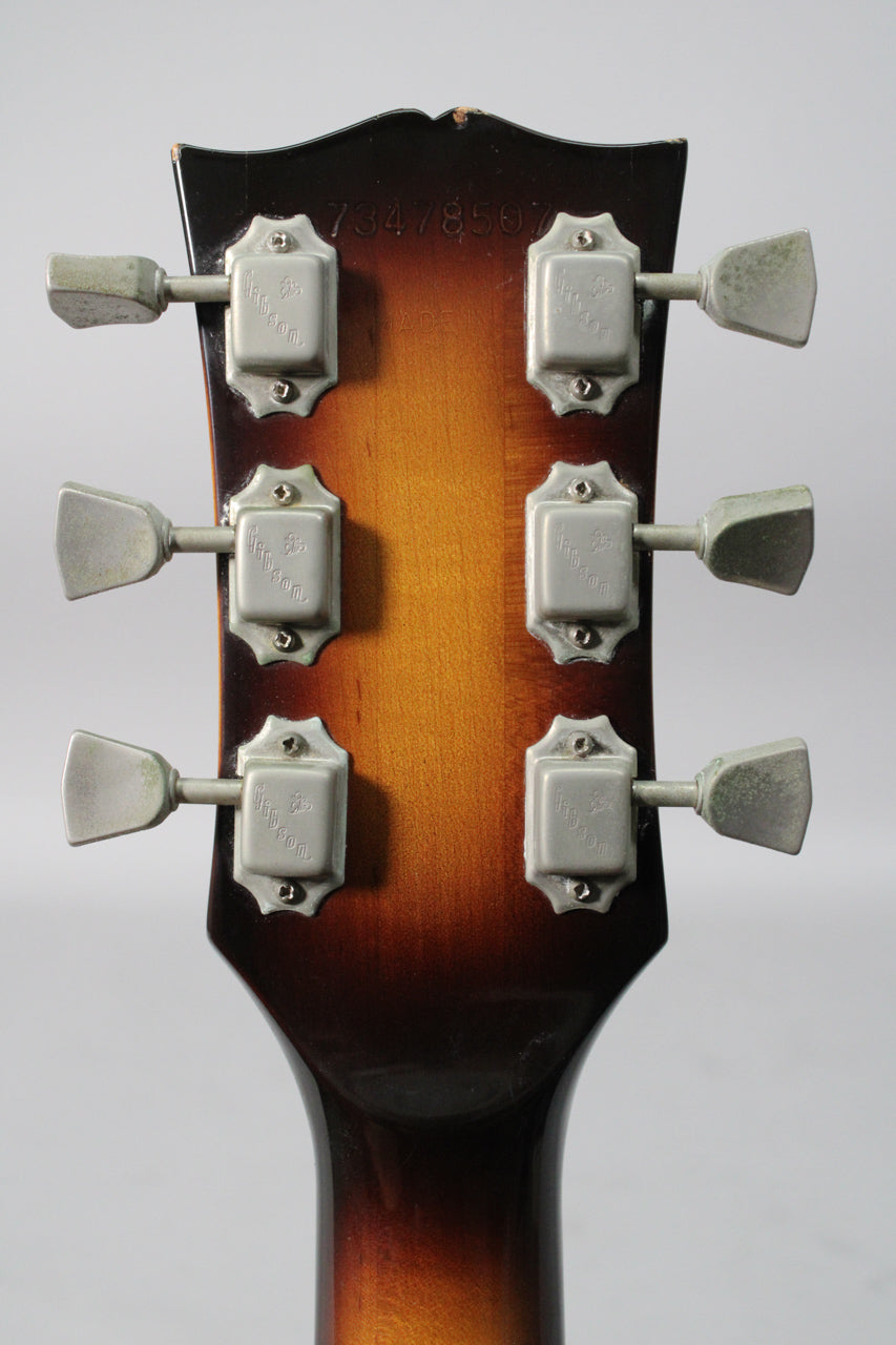 Rear view of the headstock and upper neck, showing six weathered chrome tuners on a tobacco burst finish.