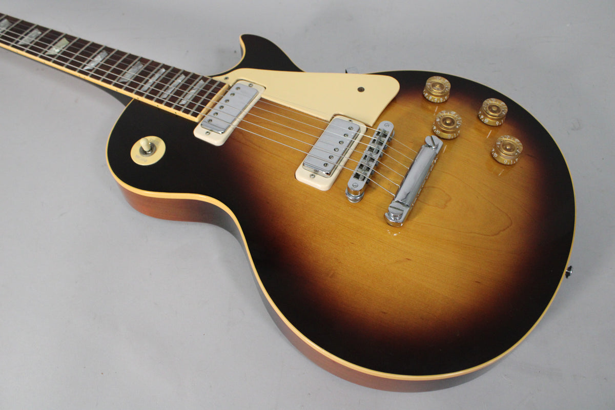 The tobacco burst guitar body, with cream binding, shows two chrome mini-humbuckers, a cream pickguard, and four amber control knobs.