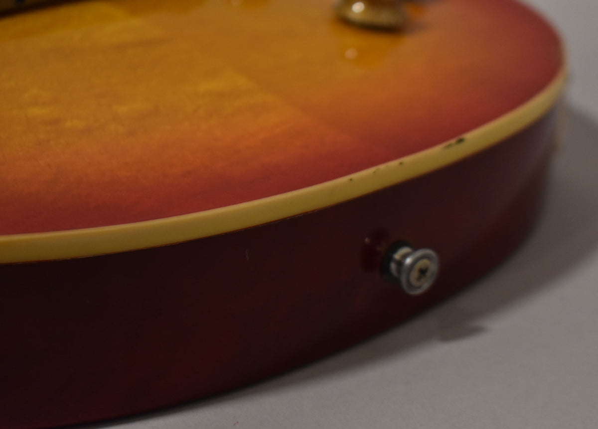 Close-up of the guitar's lower bout, showing the sunburst finish, cream binding, and output jack with some minor wear.