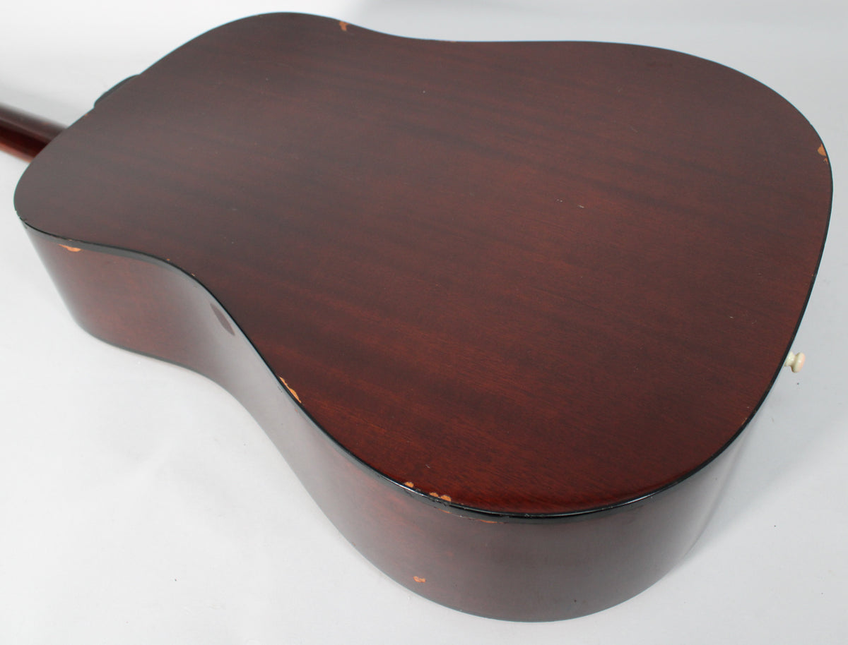 The dark reddish-brown back of the acoustic guitar is shown at an angle, with visible finish wear and chips along the edges.