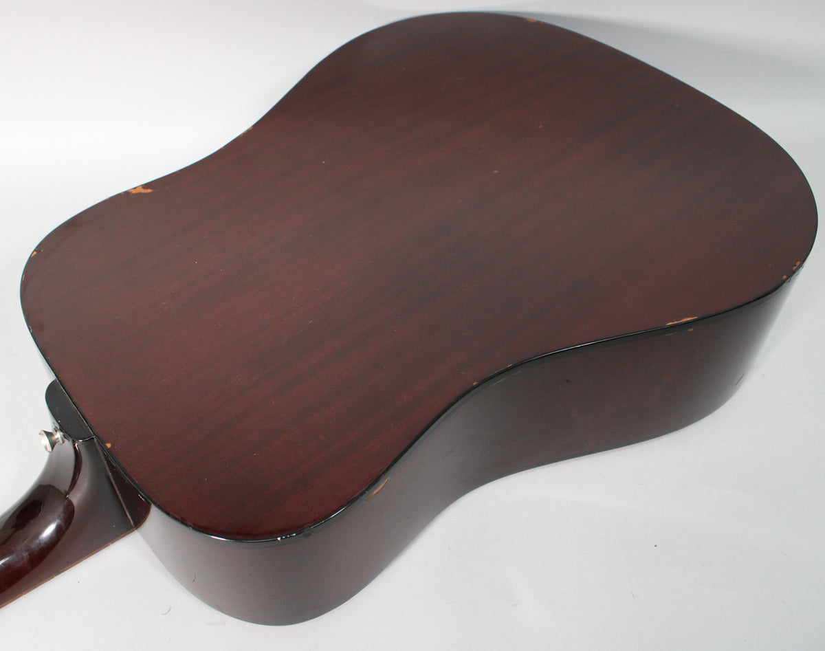 The dark reddish-brown back of the dreadnought acoustic guitar, showing finish wear and chips along the edges.