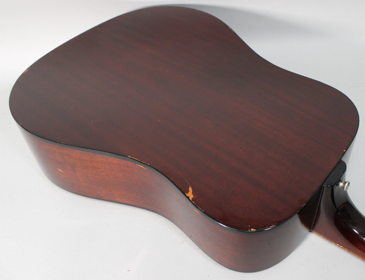 The guitar's dark reddish-brown back and side are angled, showing significant finish wear and chips along the lower bout edge.