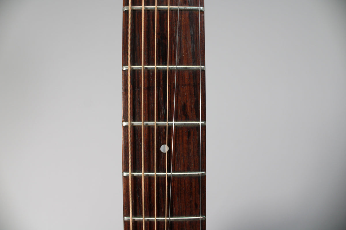 Close-up of the dark rosewood fretboard with a single white dot inlay at the 7th fret, showing light string wear.