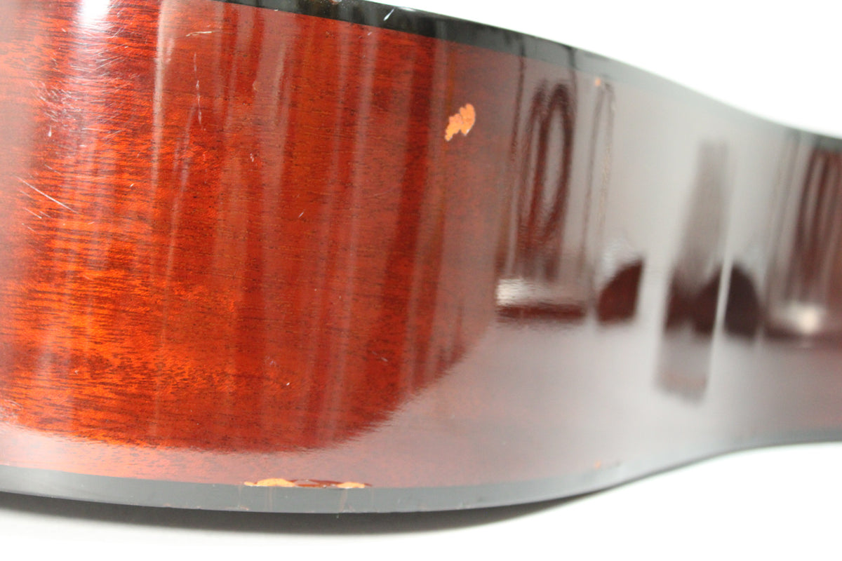 Close-up of the guitar's lower bout, showing the dark reddish-brown side with several scratches and two areas of finish wear.