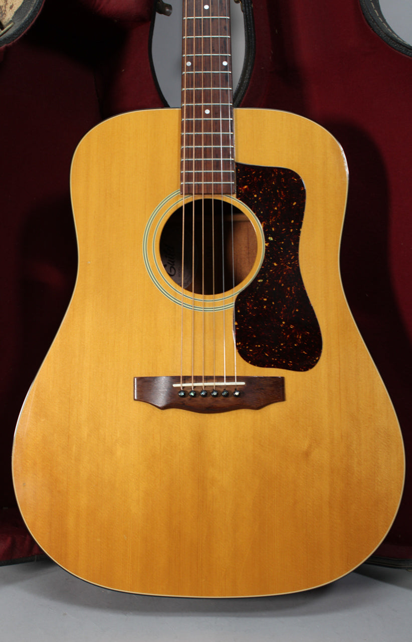 Full front view of a natural finish dreadnought acoustic guitar with a tortoiseshell pickguard and a dark wood bridge, showing light wear.