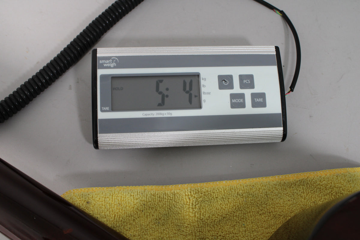 A digital scale displays "5:4" in large numbers, with a dark brown guitar body and yellow cloth visible at the bottom.