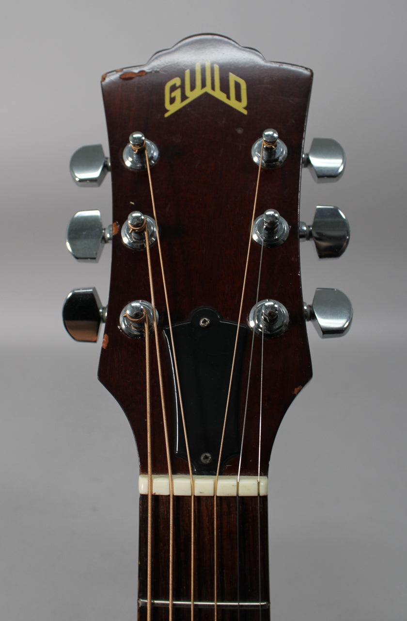 The dark brown headstock, with six chrome tuners and a black truss rod cover, shows visible wear and finish chipping.