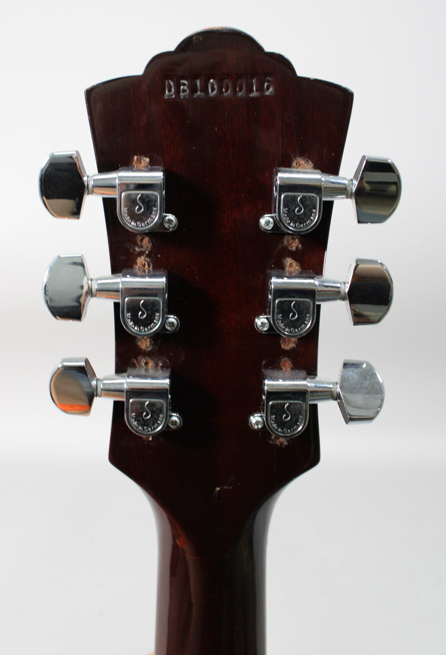 The back of the dark brown headstock and neck, showing six chrome tuners with some finish wear around their bases.