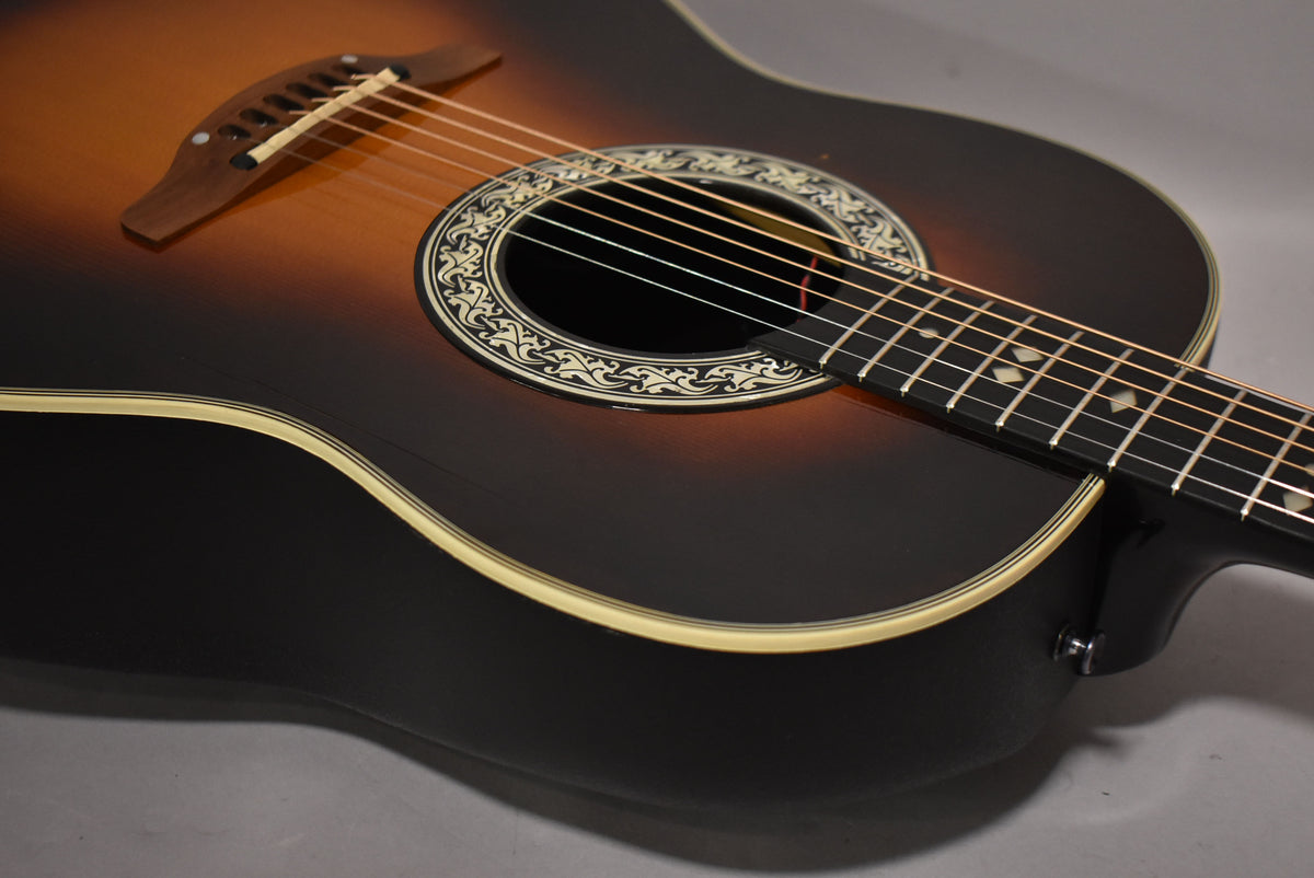 Close-up of the sunburst body, soundhole with ornate rosette, bridge, and fretboard with diamond inlays.