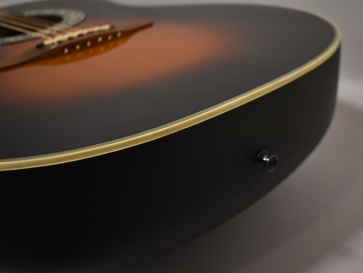 Close-up of the guitar's sunburst top and black bowl back, showing the cream binding and an endpin jack on the lower bout.
