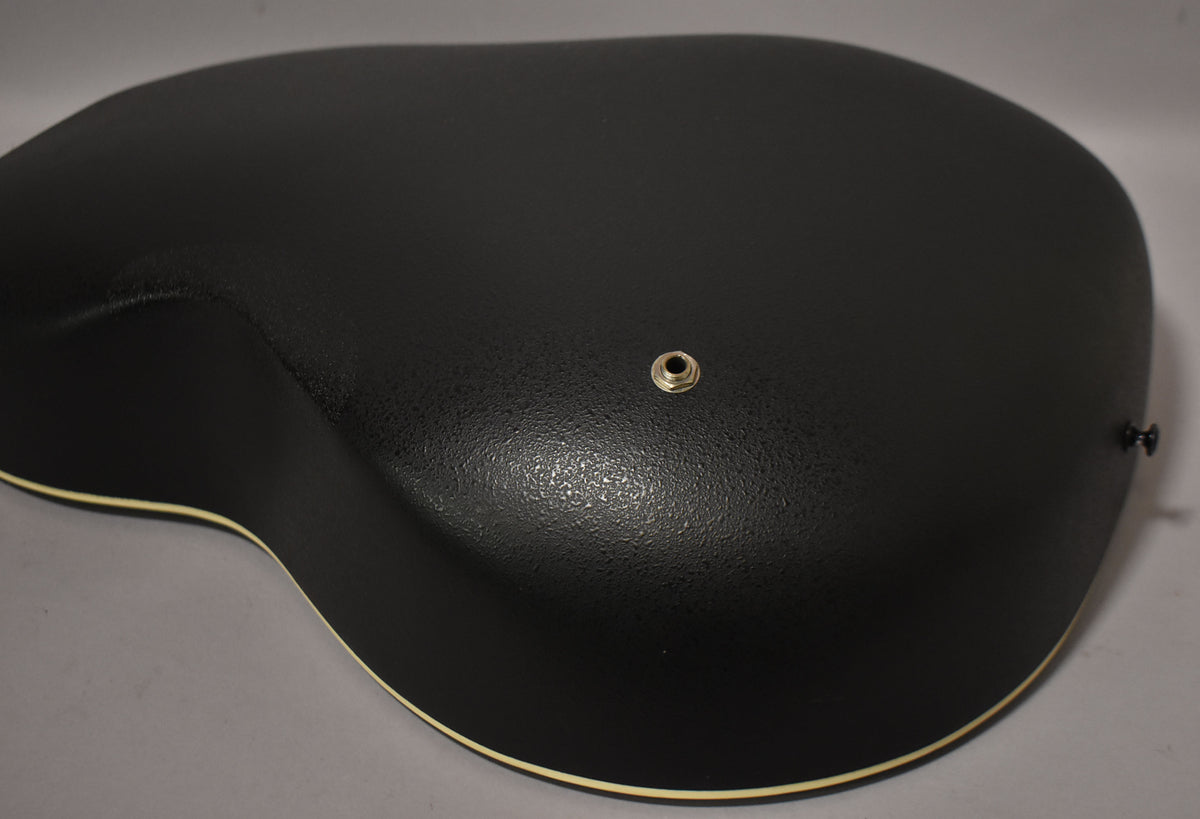 The black textured back of the guitar is angled from the upper left, showing the output jack and a strap button on the lower right.