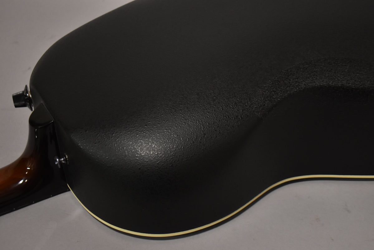 The guitar's textured black Lyrachord bowl back and lower bout are visible, with a cream binding and two strap buttons.