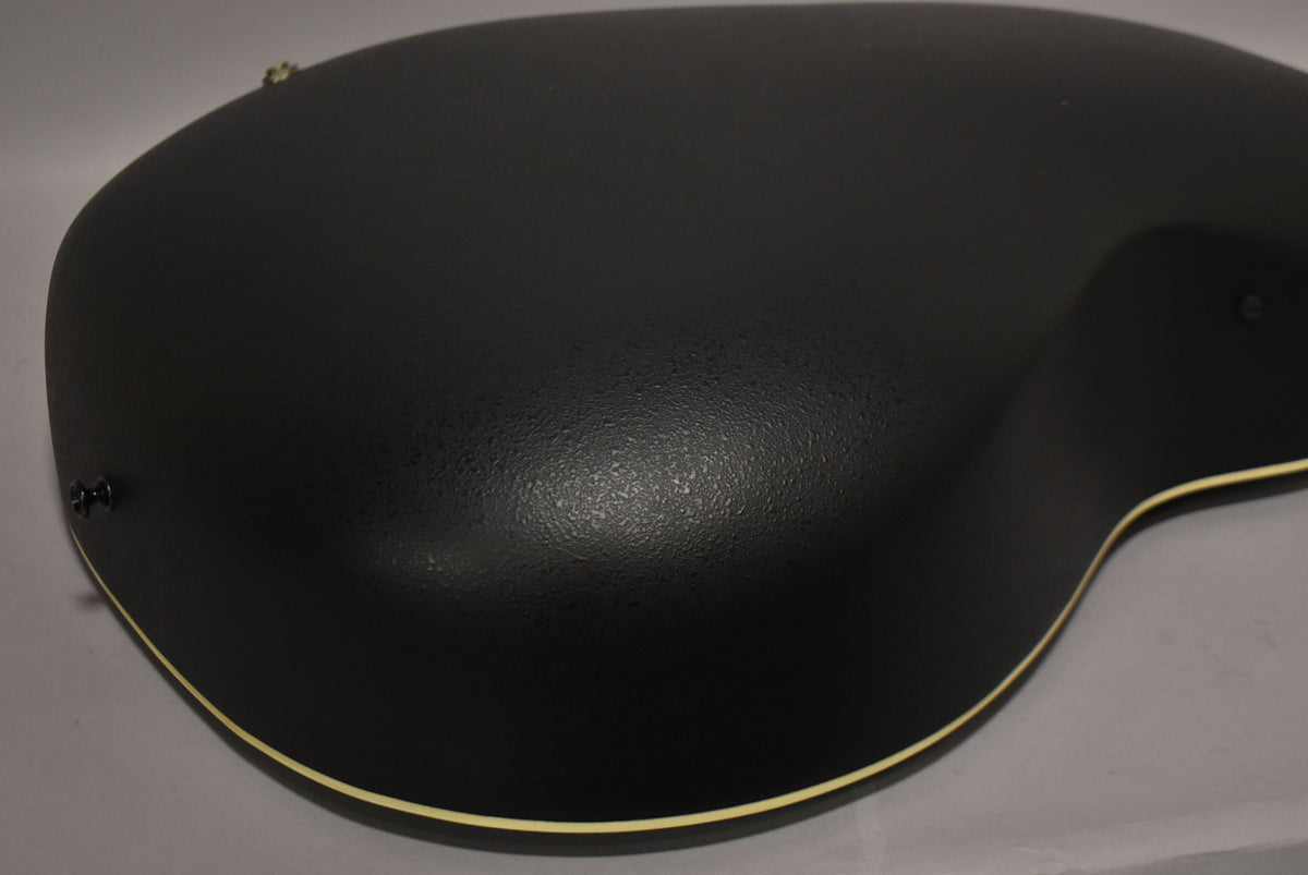 The guitar's black textured back is angled, showing the rounded bowl shape and cream binding along the edge.