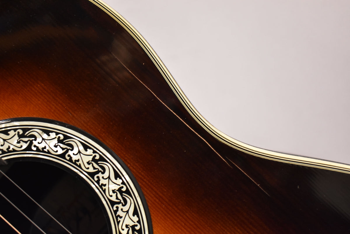 Close-up of the sunburst body with ornate soundhole rosette, showing a long finish crack and several scratches above the lower bout.