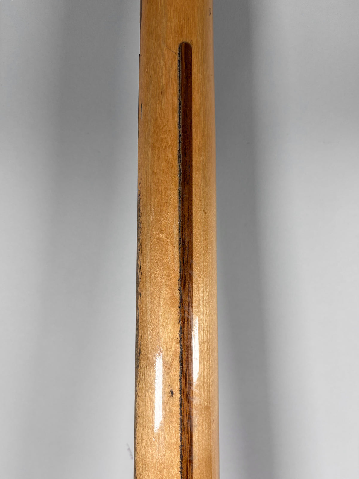 The bass neck's light wood finish shows a dark central stripe and a worn, chipped finish along the edges and center.