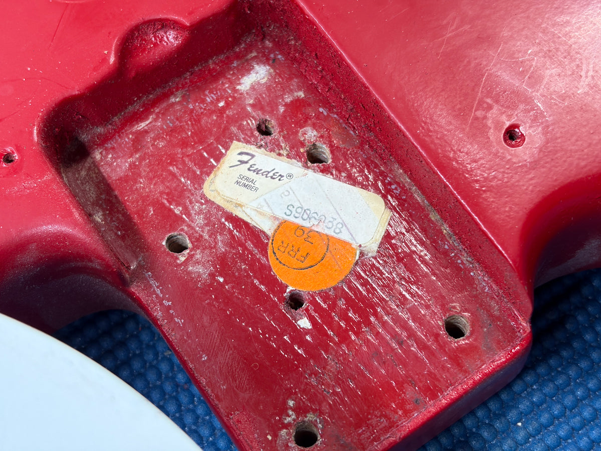 Close-up of the Moroccan Red body's neck pocket, showing a "Fender Serial Number" sticker and an orange circular sticker.