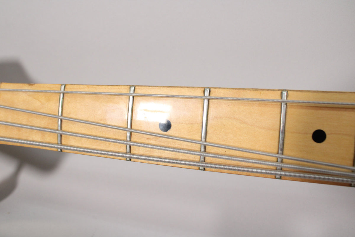 Close-up of the maple fretboard with black dot inlays and four strings, showing some light wear and a glossy finish.