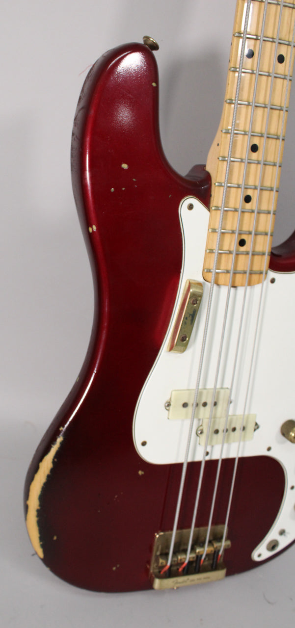 Upper body of a Candy Apple Red bass, showing a white pickguard, gold hardware, and heavy finish wear on the lower bout.