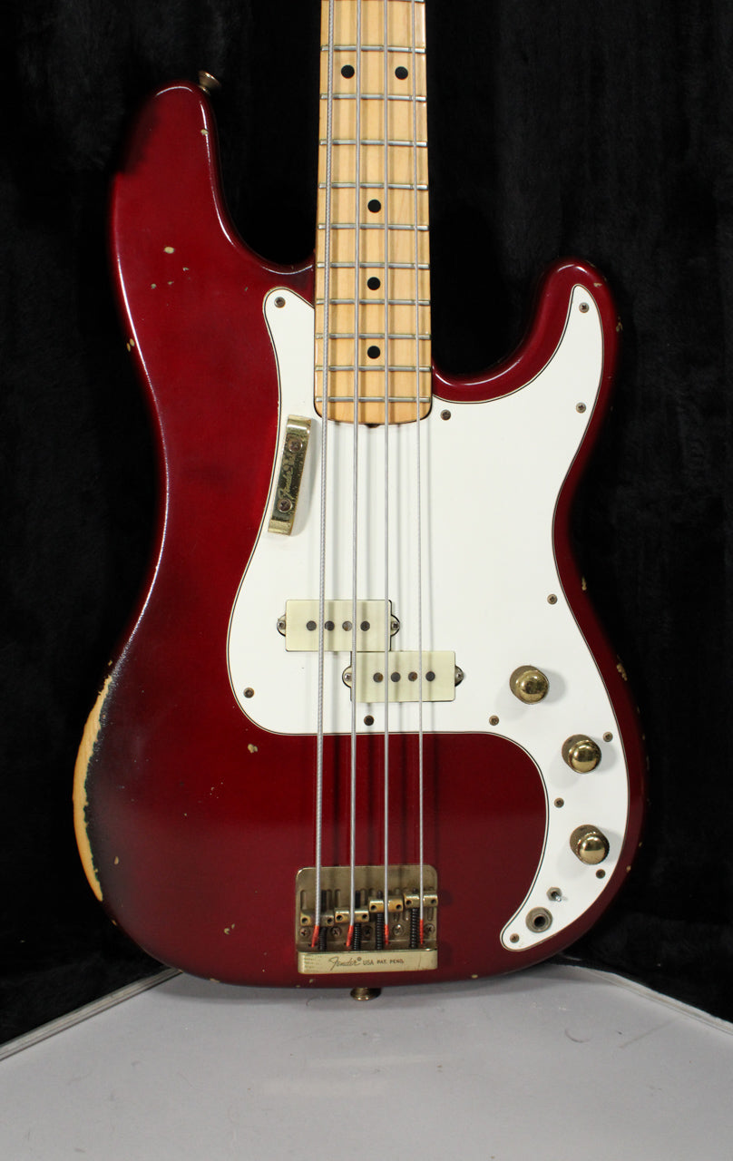 A full front view of a candy apple red bass with a white pickguard, maple neck, gold hardware, and heavy wear on the lower bout.