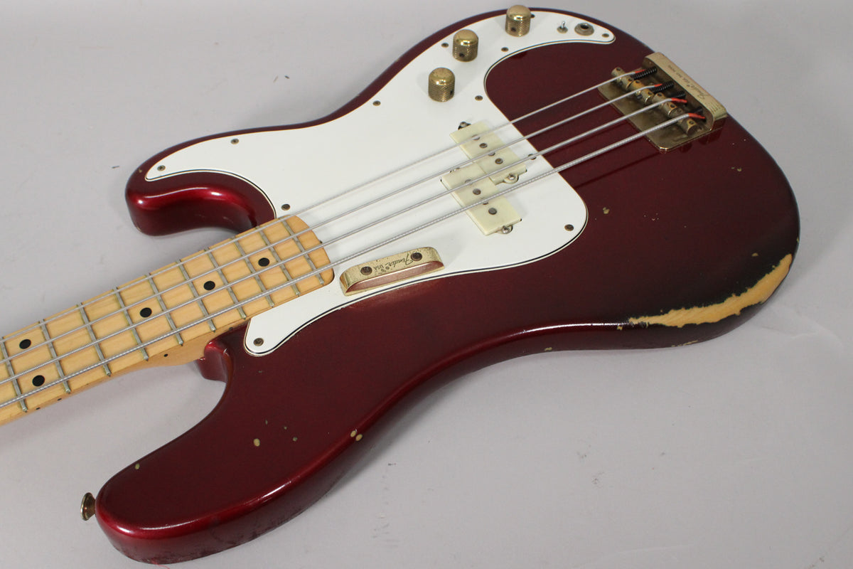 Candy Apple Red bass, angled from the neck to the lower bout, showing a white pickguard, gold hardware, and heavy finish wear.