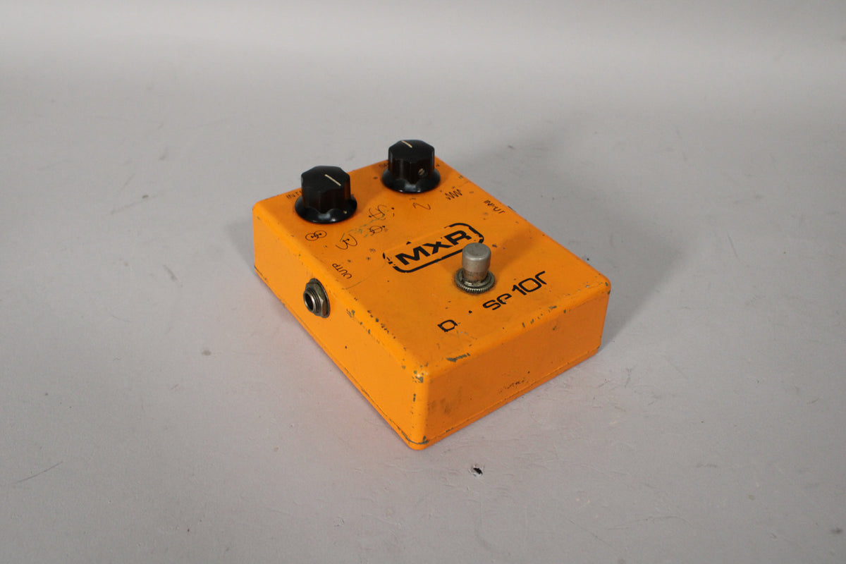 Orange pedal with two black knobs, a silver footswitch, and an output jack, showing visible paint chips and wear.
