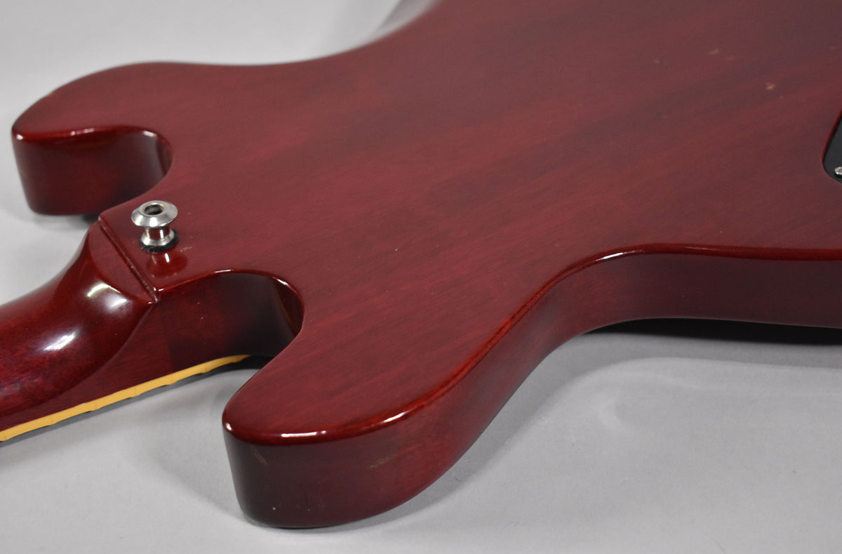 The back of the cherry red guitar body, showing the neck joint, strap button, and light wear on the glossy finish.