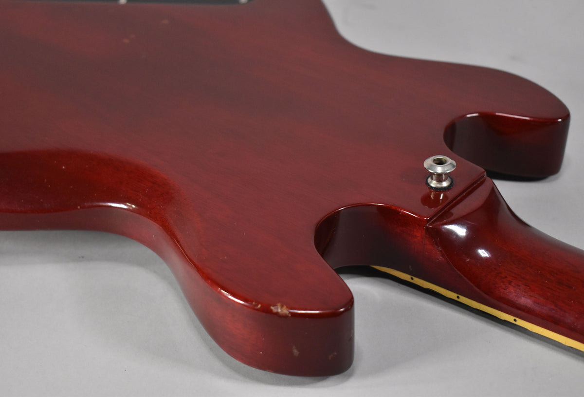 The guitar's cherry-finished body and neck join, showing the output jack and a chip on the lower horn.