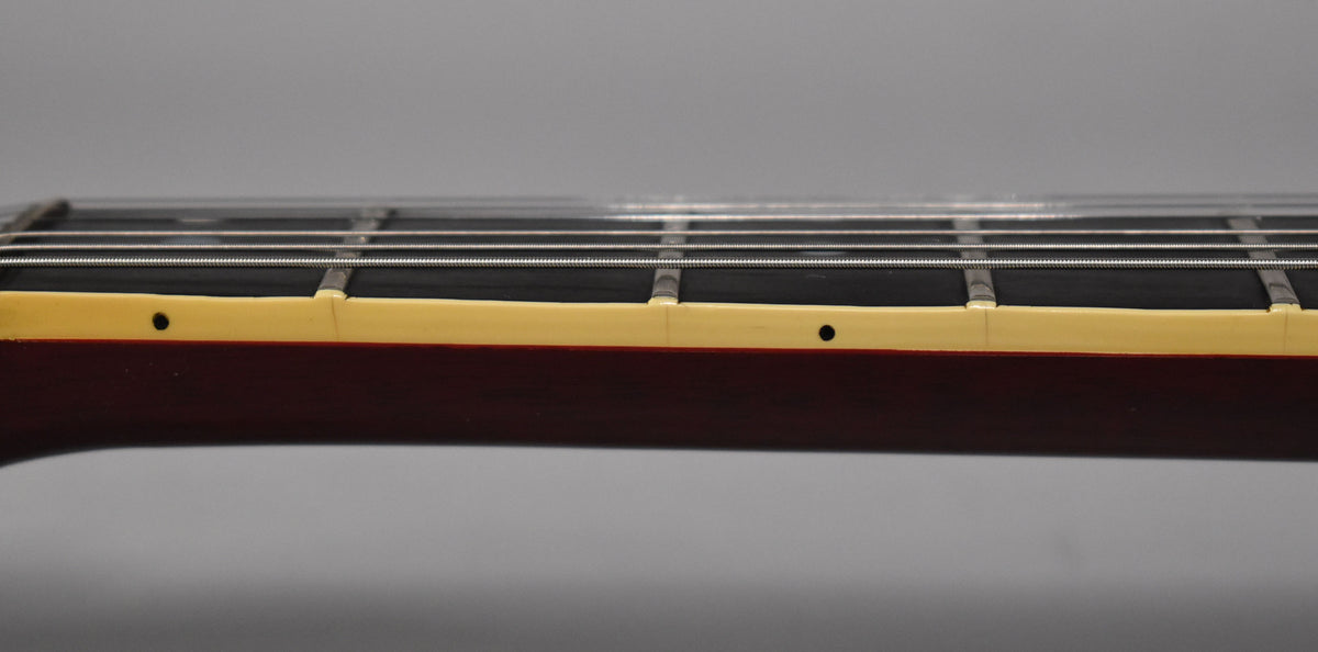 Close-up of the guitar's dark cherry neck and fretboard, showing cream binding, frets, strings, and two small dot inlays.