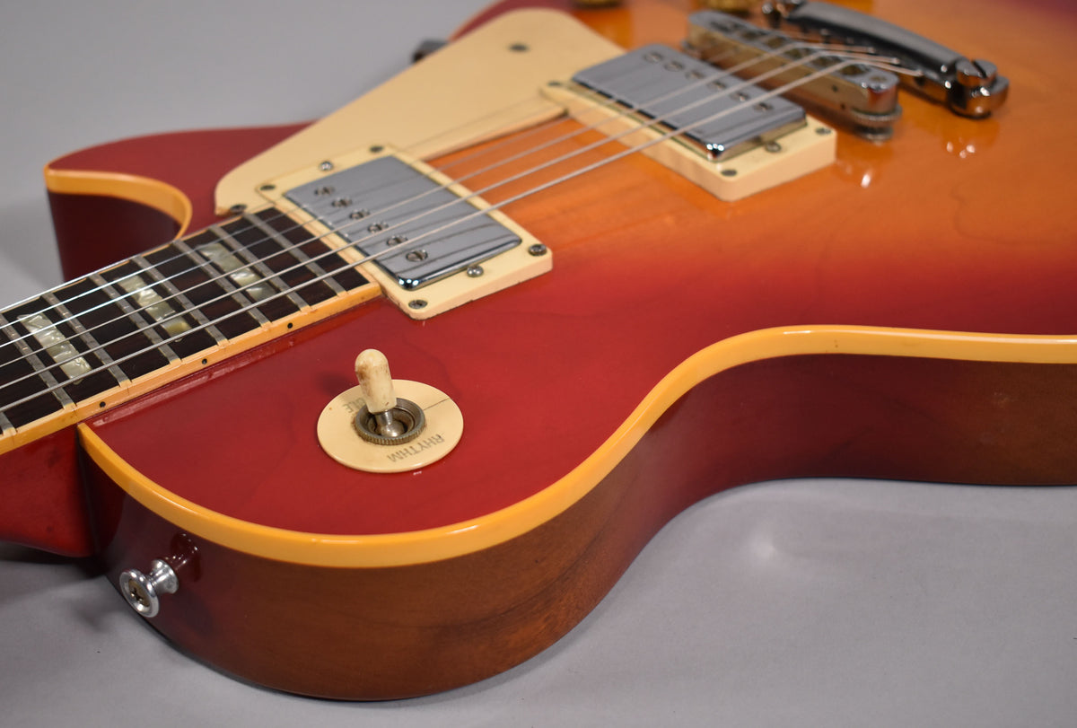 Close-up of the cherry sunburst body, showing the neck pickup, cream pickguard, output jack, and aged cream rhythm/treble switch.