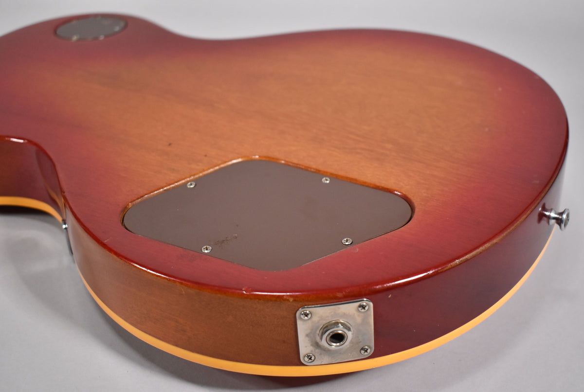 The back of a cherry sunburst guitar, showing the control cavity cover, output jack, and a few small dings on the body edge.