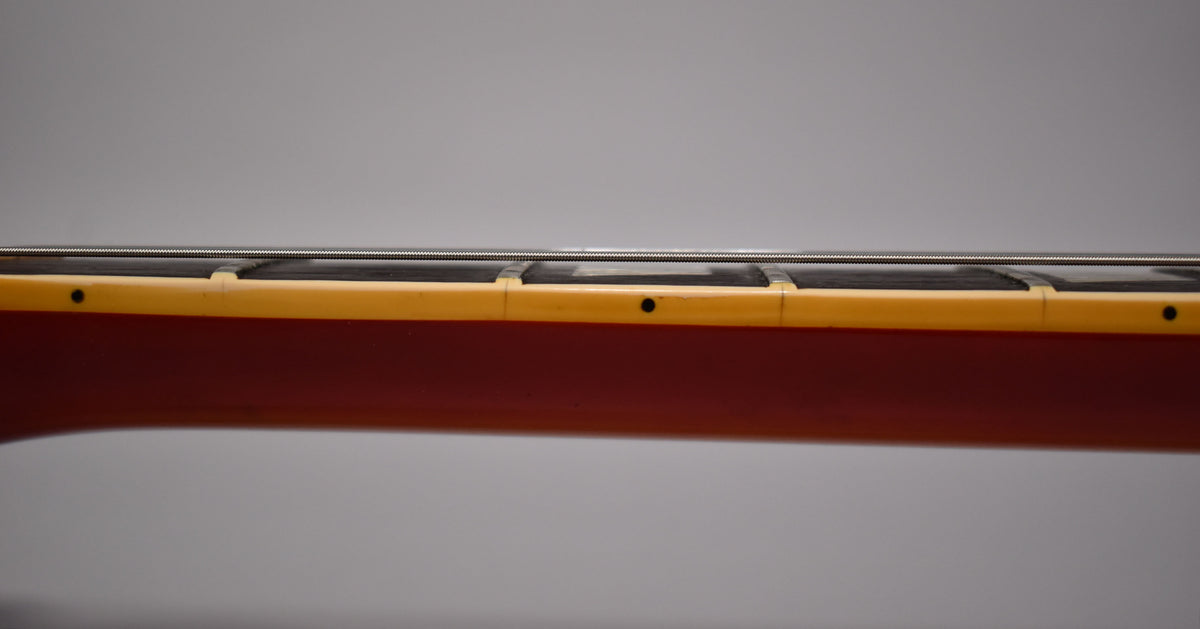 Side view of the guitar neck, showing the dark fretboard, cream binding with black dot markers, and cherry sunburst finish.