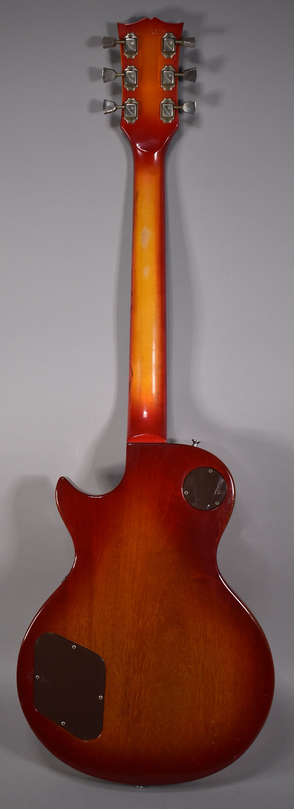 Full rear view of a cherry sunburst guitar, showing the headstock with six tuners, neck, and body with two dark brown control plates.