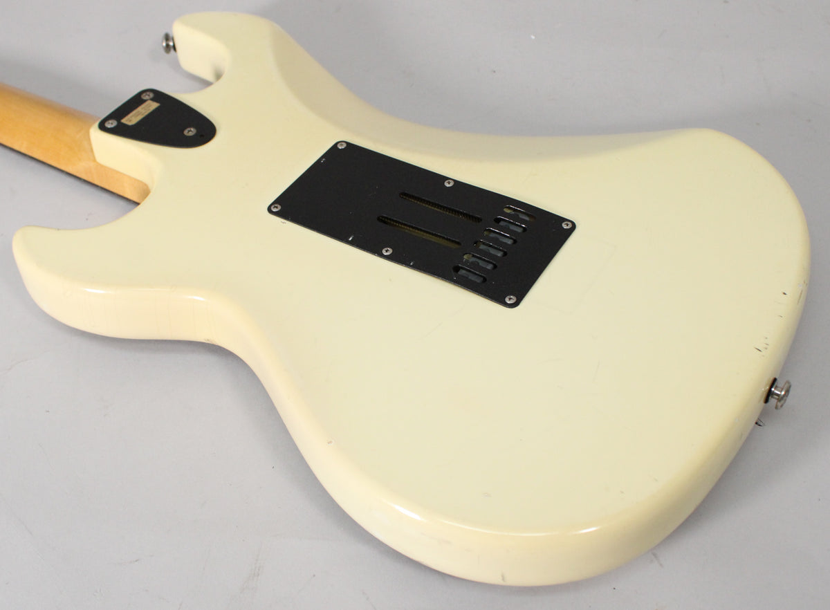 The back of the Olympic White guitar body, showing the black tremolo cavity cover and some finish checking and wear.